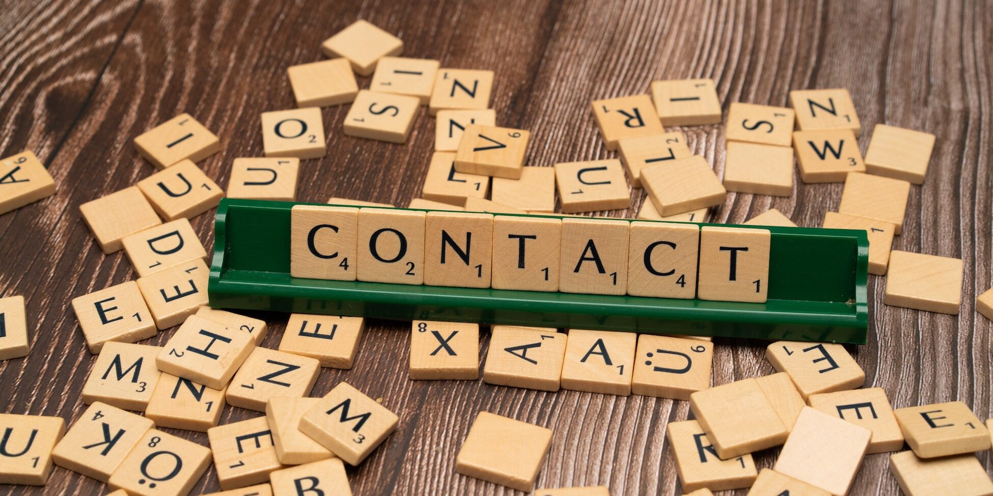 scrabble pieces with some organized to say the word contact